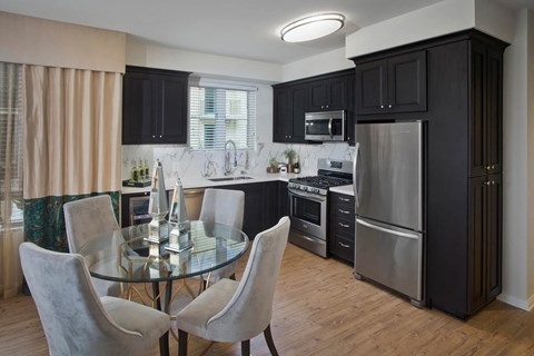 a kitchen and dining room with black cabinets and stainless steel appliances