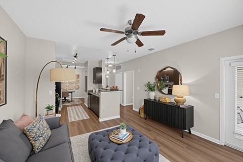 A living room with a grey couch and a round ottoman.