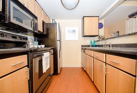 A kitchen with wooden cabinets and black appliances.