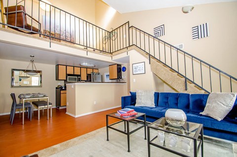A living room with a blue couch and a glass coffee table.