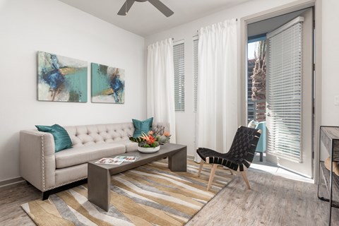 A living room with a beige couch, a coffee table, and two abstract paintings on the wall.