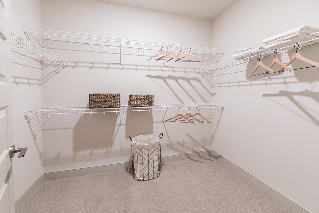 a spacious closet with shelves and racks and a trash can