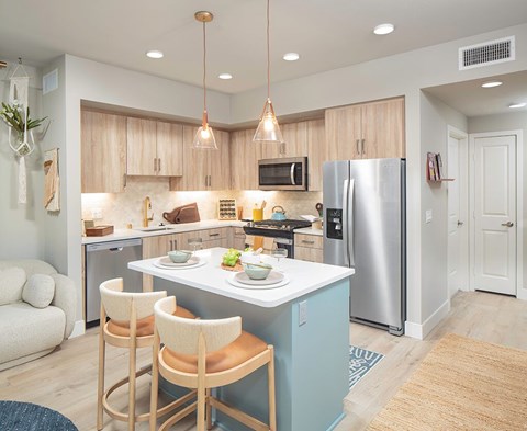 A kitchen with a blue island and wooden chairs.