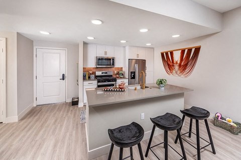 A kitchen with a bar area and three stools.
