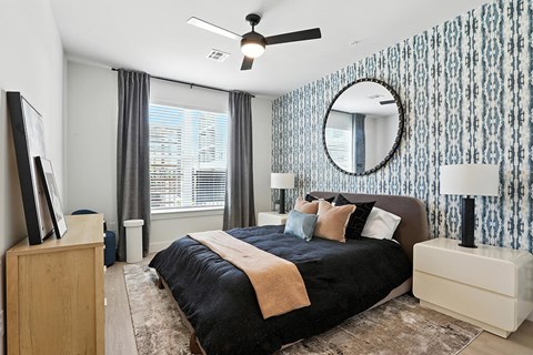 A bedroom with a black bed and a ceiling fan.