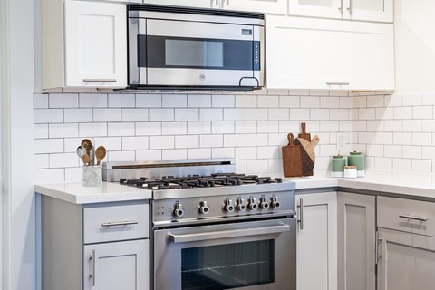 A modern kitchen with a stove top oven and a microwave above it.