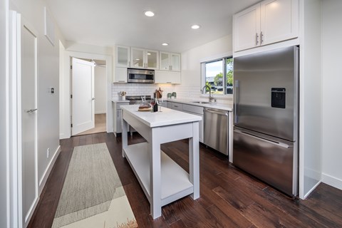 A modern kitchen with a white island and stainless steel appliances.