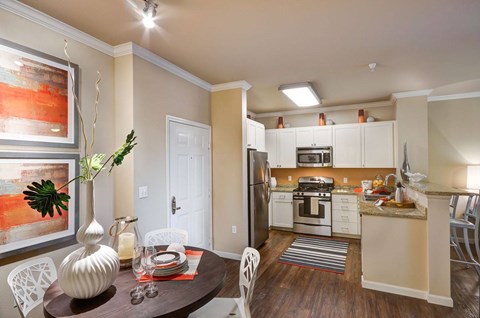 A modern kitchen with a dining table set for two.