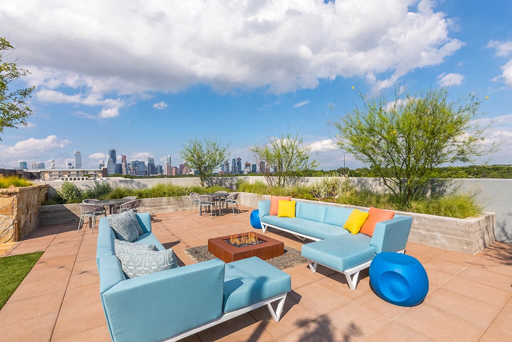 a rooftop patio with blue furniture and a view of the city
