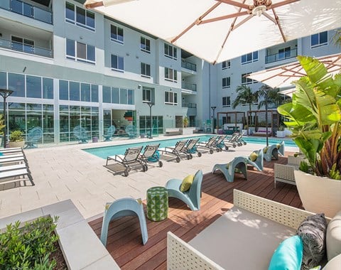 A large white building with a pool and lounge chairs.
