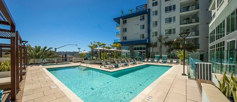 A large swimming pool surrounded by a patio and chairs.