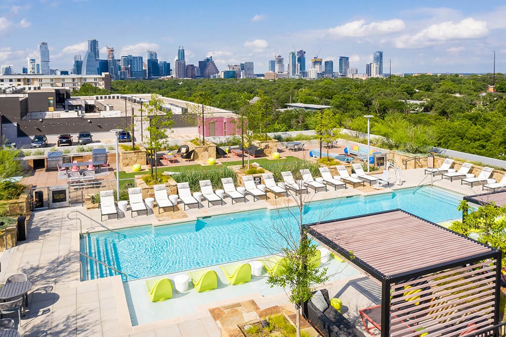 a view of a pool and the city skyline from a rooftop pool