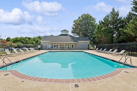 a swimming pool with chairs and a building in the background