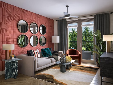 A living room with a grey couch, a table with a lamp and a vase, a rug, a fan, and a window with curtains.