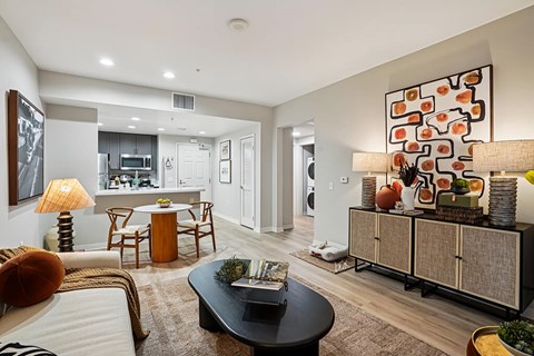 A modern living room with a black coffee table and a large abstract painting on the wall.