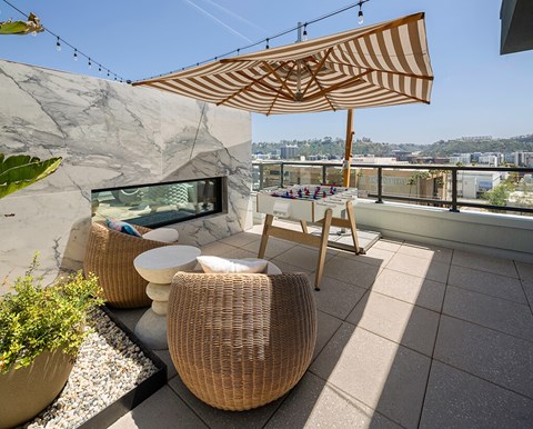 A patio with a table, chairs, and a wicker umbrella.