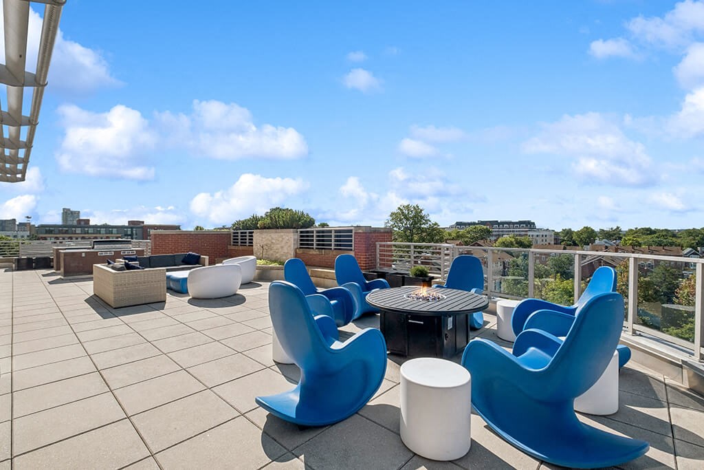 a rooftop patio with blue chairs and a table