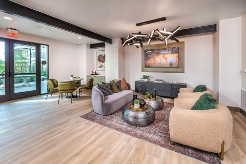 A living room with a grey couch, a green cushion, a coffee table, and a painting on the wall.
