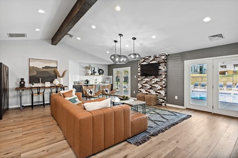 A living room with a brown sofa and a television mounted on the wall.