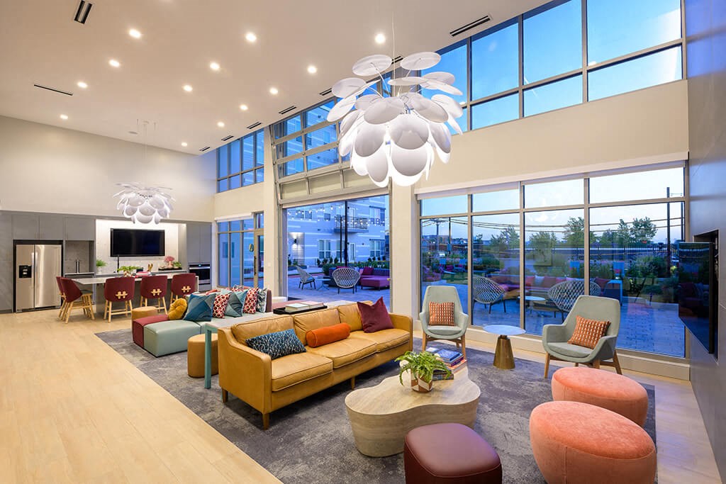 a living room with couches and chairs and large windows