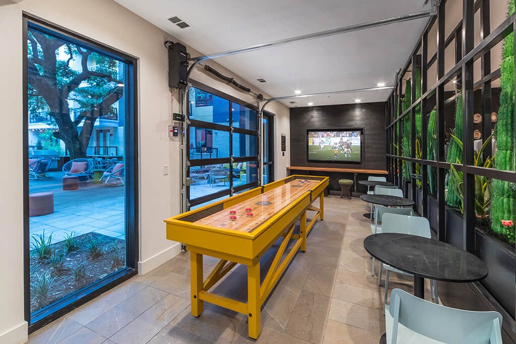 a game room with a yellow shuffleboard table and a television