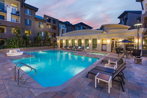 A swimming pool surrounded by lounge chairs and umbrellas in a residential area.