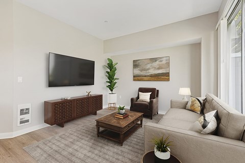 A living room with a grey couch, a brown chair, a wooden coffee table, and a painting on the wall.