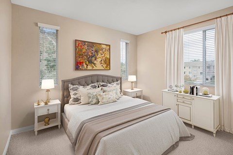 A bedroom with a large bed, a nightstand with a lamp, and a painting on the wall.