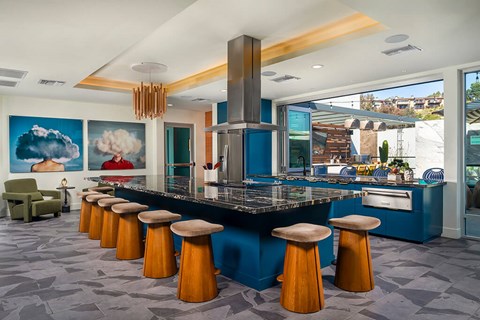 A kitchen with a blue counter and orange stools.