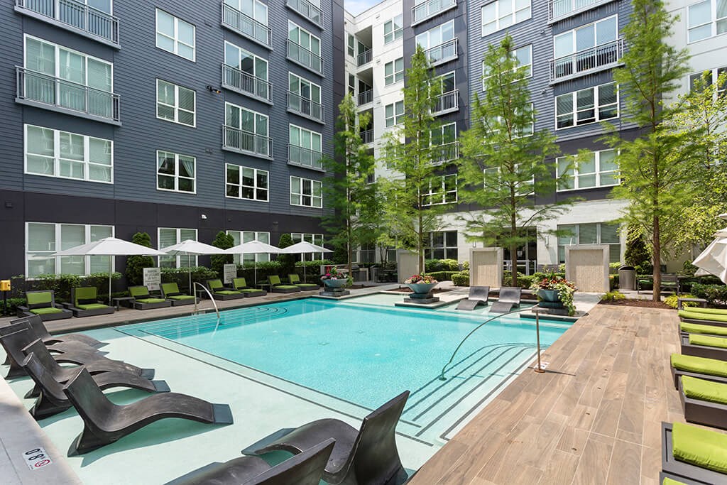 an outdoor pool with lounge chairs and umbrellas  at Cirro King of Prussia Apartments in King of Prussia, PA