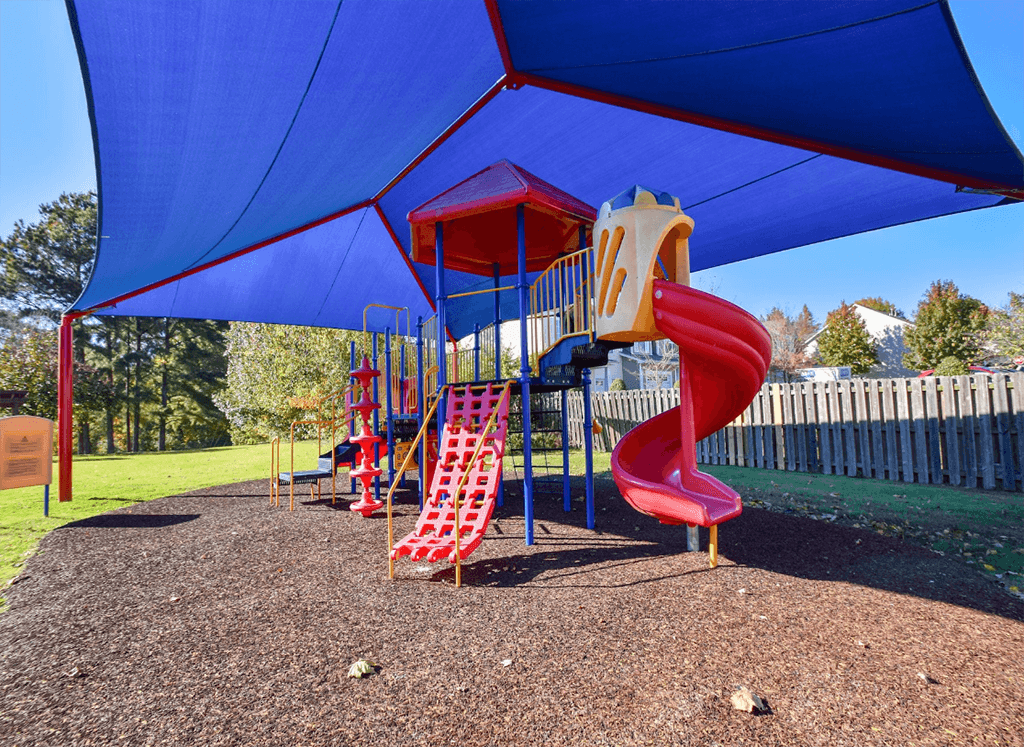 A playground with a red slide and a blue canopy.
