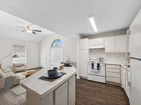 A kitchen with white cabinets and a wooden floor.