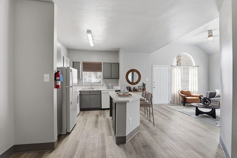A kitchen with a refrigerator, sink, and a dining table with chairs.