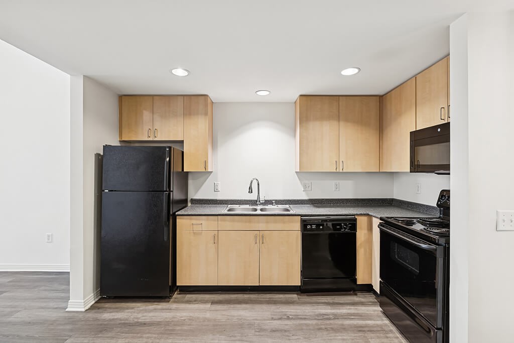 A kitchen with black appliances and wooden cabinets.