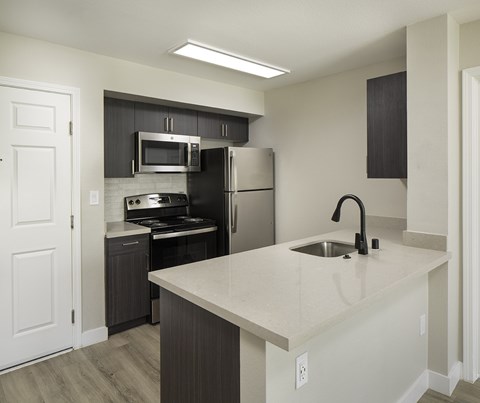 A kitchen with a white countertop and black cabinets.