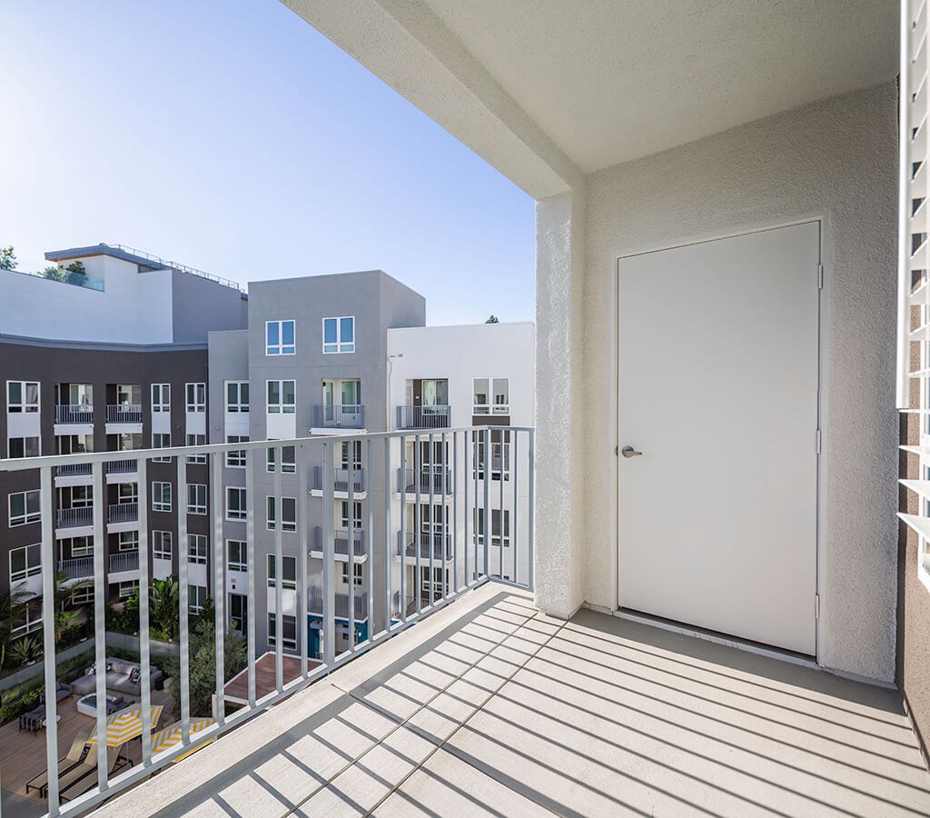 A balcony with a white door and a view of apartment buildings.
