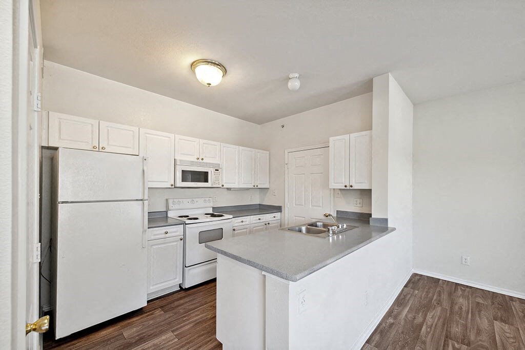 Apartments in North Dallas TX - Tivoli - Galley Kitchen with White Cabinetry, Grey Countertops, and All White Appliances