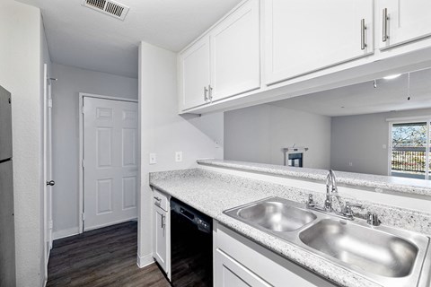 a kitchen with a stainless steel sink and white cabinets