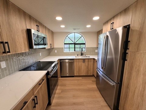 A kitchen with wooden cabinets and a stainless steel refrigerator.