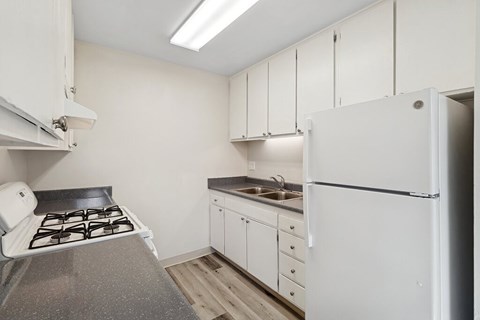 A kitchen with white cabinets and a white fridge.