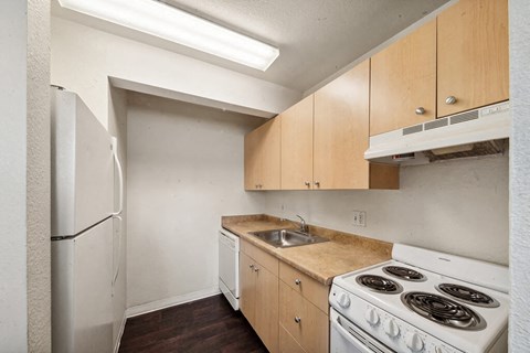 an empty kitchen with white appliances and wood cabinets