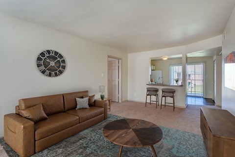 A living room with a brown couch and a clock on the wall.