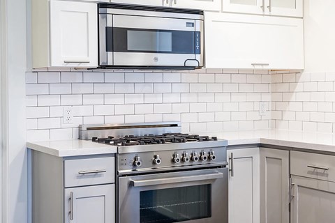 A modern kitchen with a stove top oven and microwave above it.