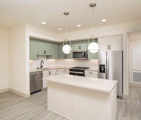 A modern kitchen with a white countertop and green cabinets.