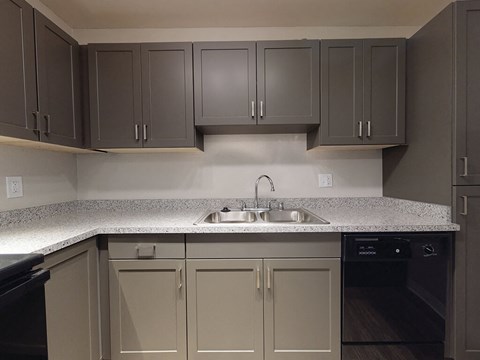 a kitchen with white counter tops and gray cabinets