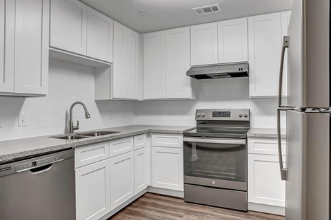 A modern kitchen with white cabinets and stainless steel appliances.