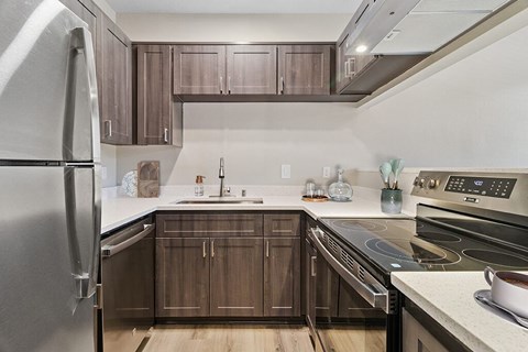 A modern kitchen with dark wood cabinets and stainless steel appliances.