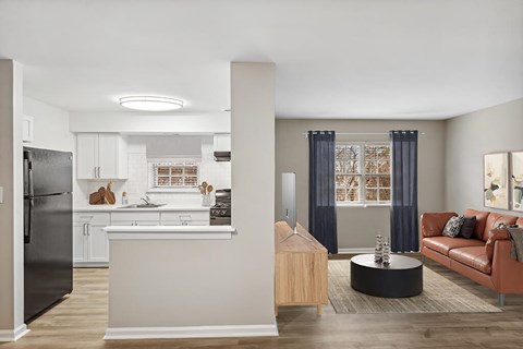 A modern kitchen with a black refrigerator and a brown leather sofa.