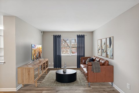 A living room with a brown leather couch and a wooden cabinet.