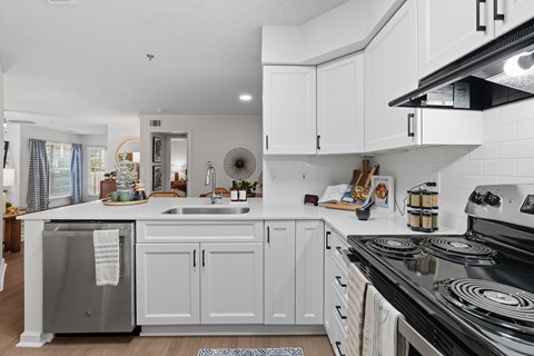 A modern kitchen with white cabinets and a black stove top.